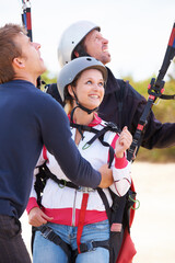 Taking off. Two paragliders ready to do a tandem jump being assisted by an instructor.