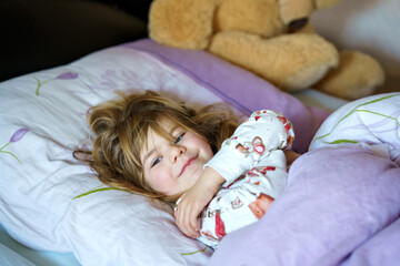 Cute little preschhol girl after sleeping in bed. Happy joyful smiling child wake up in the...