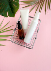 Shopping trolley full cosmetic goods on pink background. Black friday concept. Sale and discount. Goods for women. Closeup of a basket with cosmetic products.