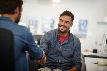 Great doing business with you. Shot of two young businessmen shaking hands together at a desk in an office.