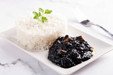 Squid in ink sauce and rice on white background