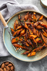 Honey garlic butter roasted carrots on a concrete background. Roasted carrots prepared with garlic butter and sweet honey sauce. Homemade glazed carrots
