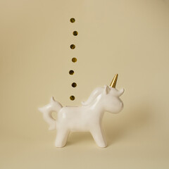 White unicorn piggy bank with gold coins on minimal yellow background © Sahara 02