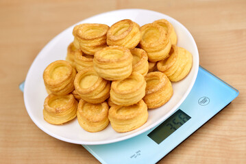 A vol-au-vent dish lies on the blue scales. Calorie counting concept, figure tracking