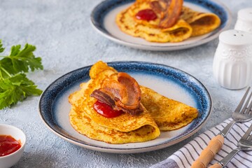 Swedish Ragmunk potato pancakes with fried bacon and berry sauce on a ceramic plate on a gray concrete background. Swedish cuisine.