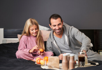 daughter and father having breakfast in bed