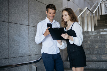 young employees with a clipboard standing on the steps in the office.