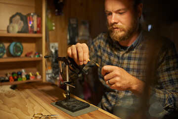Creating the perfect fishing tackle. Shot of a man making fishing lures in his workshop.