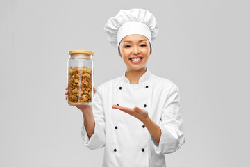 cooking, culinary and people concept - happy smiling female chef holding jar with pasta over grey background