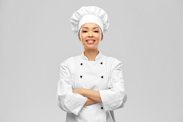 cooking, culinary and people concept - happy smiling female chef in white jacket over grey background