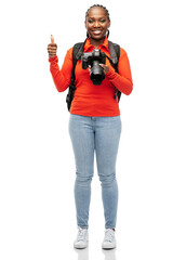 people, profession and photography concept - happy smiling woman photographer with digital camera and backpack showing thumbs up over white background