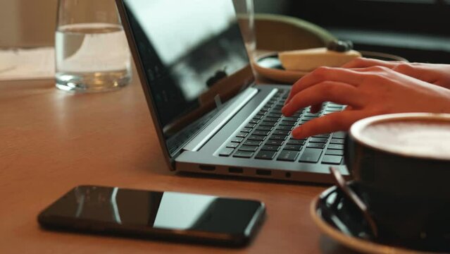 Typing on a laptop in a cafe