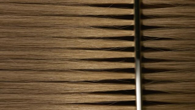 Vertical shot of honey brown hair being combed with silver comb | Hair dye commercial