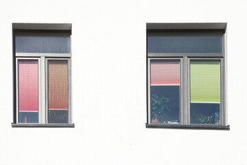 Fenster mit bunten heruntergezogenen Rolläden an einer weißen Hauswand, Deutschland, Europa