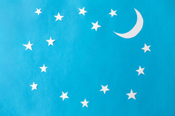 night, bedtime and object concept - moon and stars on blue paper background