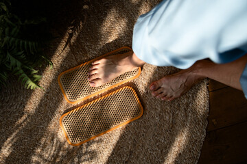 Barefoot woman foot stands on a wooden board with nails for concentration practice.