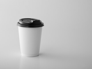 White takeaway paper cup with black plastic lid. .
