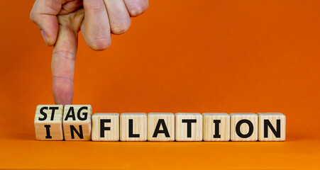 Stagflation or inflation symbol. Businessman turns cubes and changes the concept word inflation to...