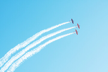 Three light engine airplane flying in a cloud of smoke in the blue sky.