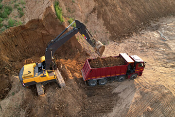 Earthmoving at construction site. Excavator load soil in dump truck. Excavator on earthworks. Open pit development and sand mining. Loader digg ground for foundation pit. Earthmover and digger.. © MaxSafaniuk
