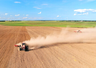 Obraz premium Cultivated land and soil tillage. Tractor with disc cultivator on land cultivating. Agricultural tractor on cultivation field. Tractor disk harrow on plowing field. Soil cultivation, Plough plowed.