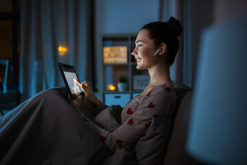 technology, bedtime and people concept - happy smiling teenage girl with tablet pc computer and...