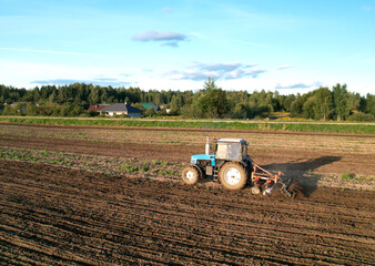 Obraz premium Cultivated land and soil tillage. Tractor with disc cultivator on land cultivating. Agricultural tractor on cultivation field. Tractor disk harrow on plowing field. Soil cultivation, Plough plowed.