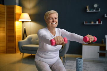 Fototapeta na wymiar Senior woman training with dumbbells at home