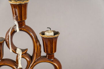 Brown ceramic candlestick with extinguished melted candles. Small white candle stubs. Gray...