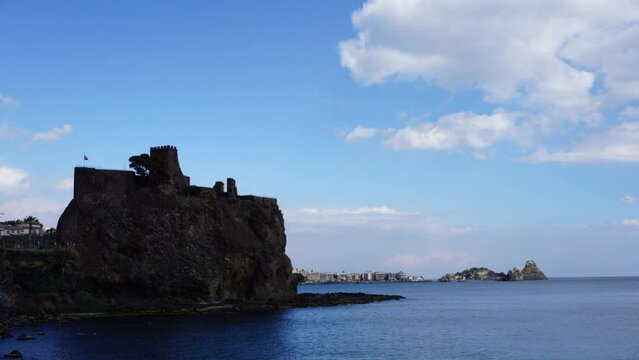 Time Lapse di un paesaggio marittimo, con le nuvole che scorrono veloci sul castello e i faraglioni di Aci Trezza in Sicilia