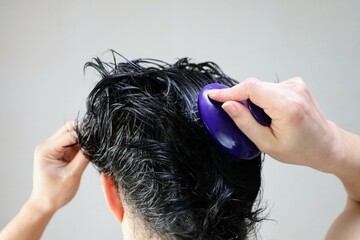 ヘアブラシで頭皮をマッサージする日本人男性