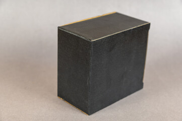 Rectangular black box on a gray background. Closed cardboard package with correct geometric shape.