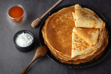 Stack of russian thin pancakes blini with fresh sour cream and honey