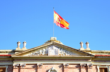 Spain flag on a building against a blue sky.