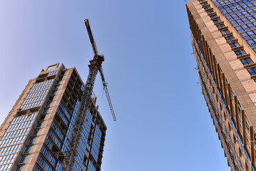 Tower crane on the construction of a residential building. Construction site with cranes for building construction. Tower cranes in action. Housing renovation and Real Estate concept.