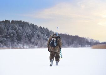 Ice fishing on frozen lake. Fishermen in camouflage clothing is walking on frozen lake for ice fishing. Fisherman on lake with drill for drilling holes in the ice for catching fish. Winter fishing.