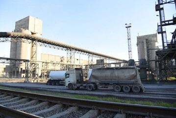 Fototapeta na wymiar Truck with cement semi-trailer at cement plant site. Сement mix production at industrial factory. Industrial plant for the production of dry construction mixes. Concrete-mixing plant. Dry mix mortar.