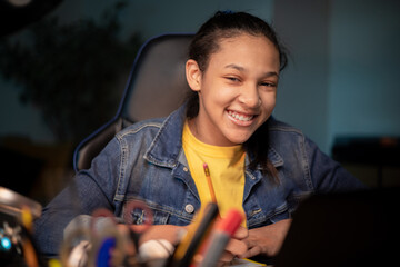 Portrait of a pretty young teenage girl studying while sitting at a desk with a laptop at home, the...