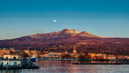 Fototapeta na wymiar Panorama della citta di Riposto ed Etna con tramonto di luna piena