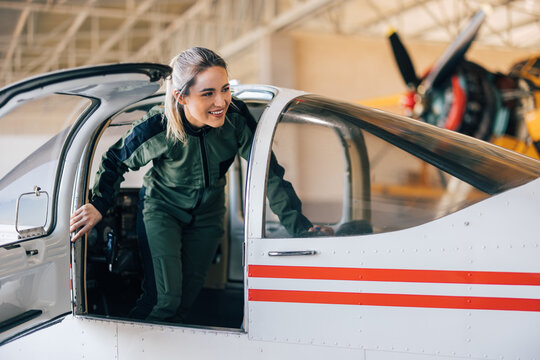 Confident caucasian woman pilot, getting out of the cockpit.