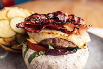 Close up of a juicy delicious cheeseburger with bacon and a lot of vegetables.