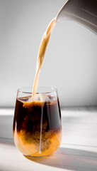 iced or frozen bumble coffee in a glass, splash with drops, over grey background