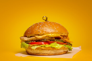 Juicy Burger with Chicken Cutlet on a yellow background. Chicken Meat and Fresh Tomatoes 