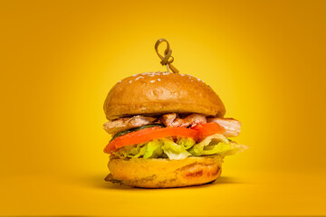 Juicy Burger with Chicken Cutlet on a yellow background. Chicken Meat and Fresh Tomatoes 