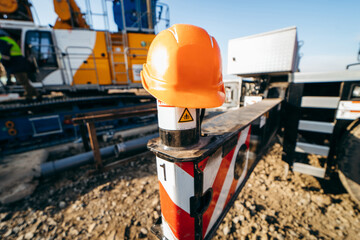Orange construction plastic hard hat on the background of construction equipment