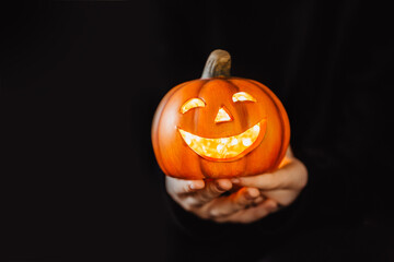Halloween - kleiner Kürbis in Hand vor schwarzen Hintergrund 
