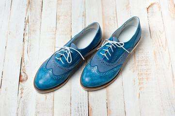 Blue imitation leather shoes laced with white laces. Close-up shot.
