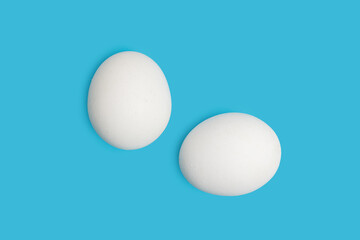 White chicken eggs on blue background, top view