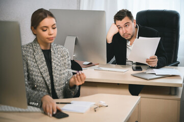 Obraz premium Young attractive woman and adult man are working in the office. Open space concept for teamwork