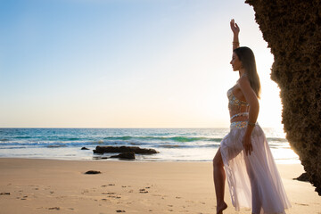 Happy and calm woman poses on the beach wearing the typical belly dance costume. Exotic beauty....